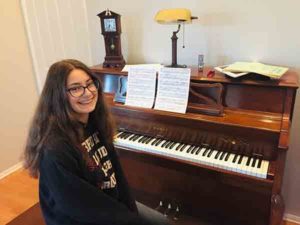 Student Heavyn at her piano smiling